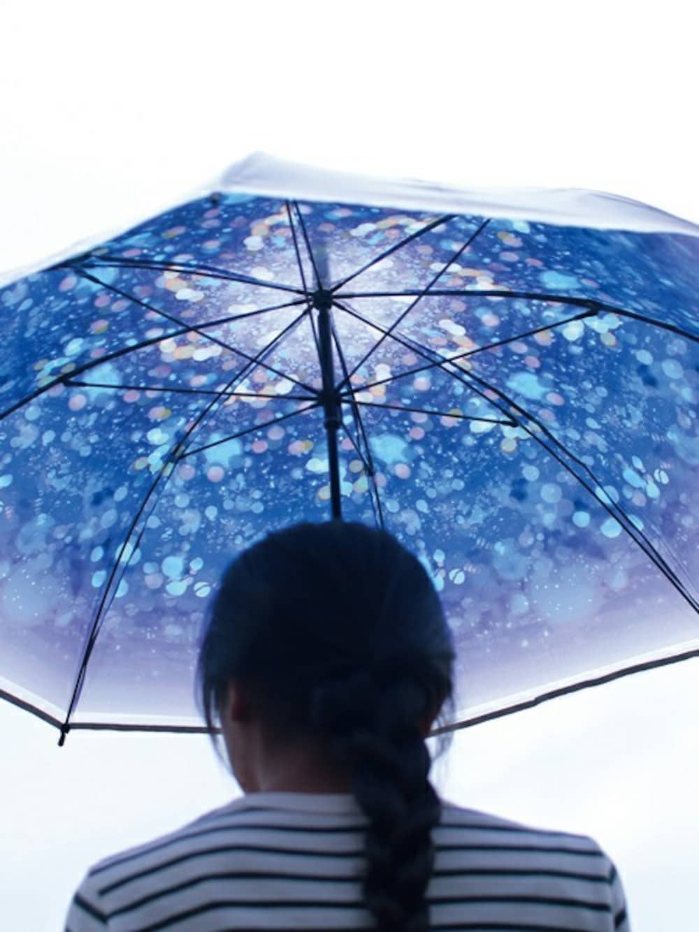 ブルー系の長傘を着用したレディースの春コーディネートの1枚目の写真