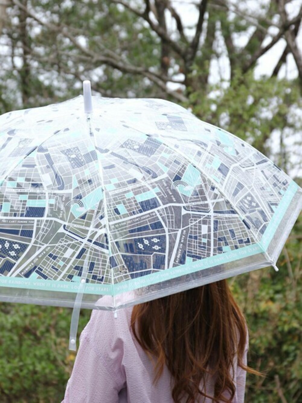 グリーン系の長傘を着用したレディースの秋コーディネートの1枚目の写真