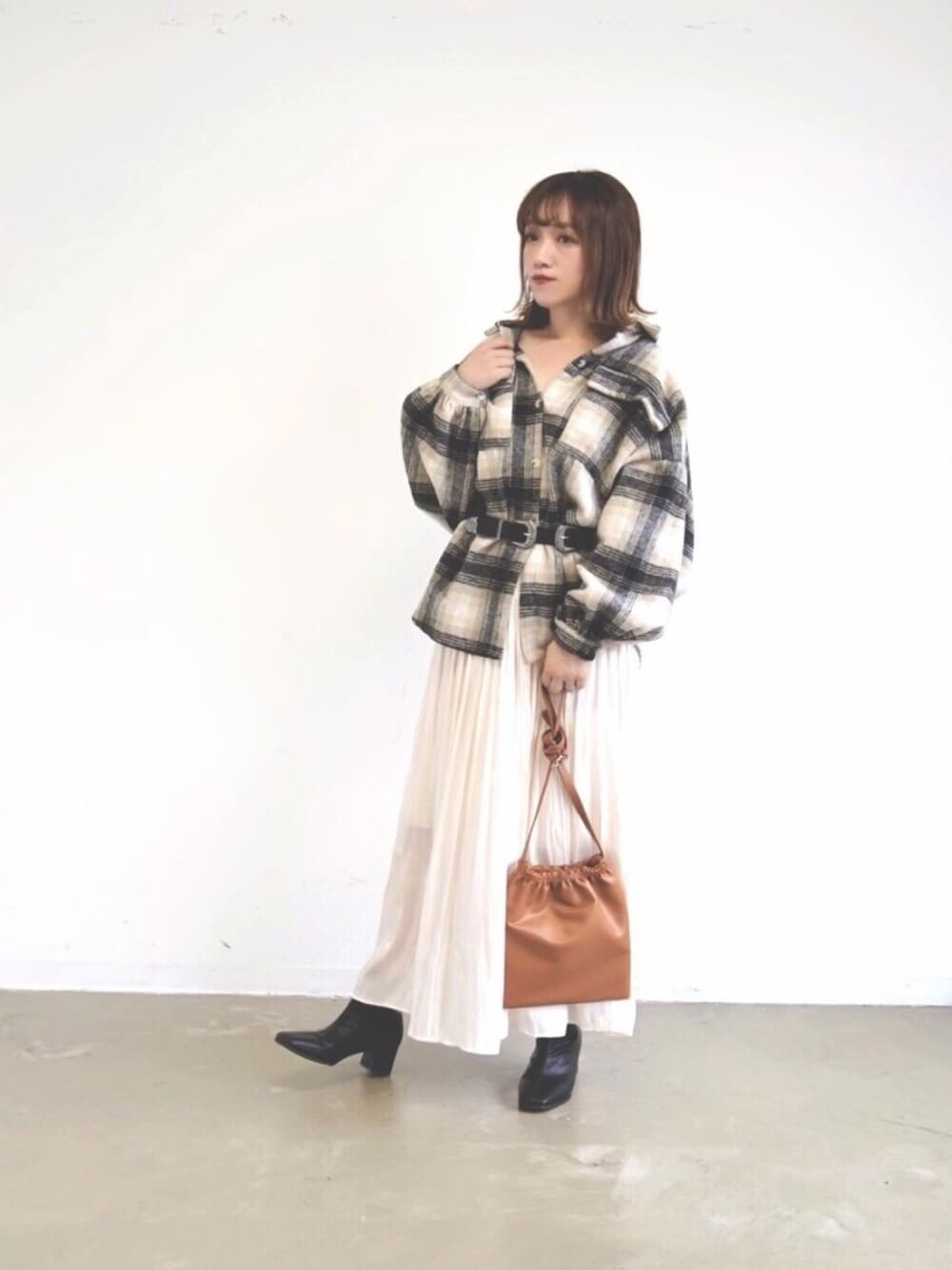 ブラック系のシャツ/ブラウス、ベージュ系のスカート、ブラック系のブーツを着用したレディースの秋コーディネートの1枚目の写真