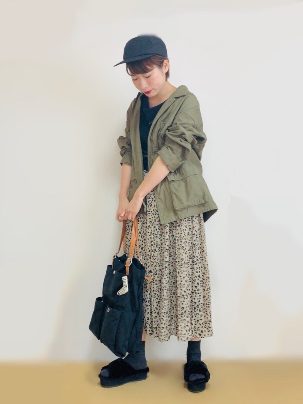 グリーン系のミリタリージャケット、ブラック系のTシャツ/カットソー、ベージュ系のスカートを着用したレディースの秋コーディネートの1枚目の写真