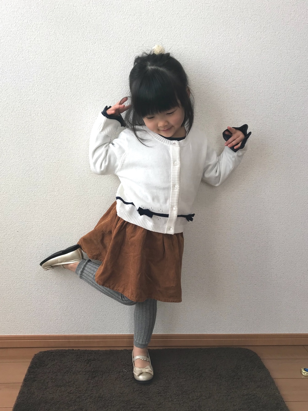 ホワイト系のカーディガン/ボレロ、ブルー系のTシャツ/カットソー、ブラウン系のスカートを着用したキッズの冬コーディネートの1枚目の写真