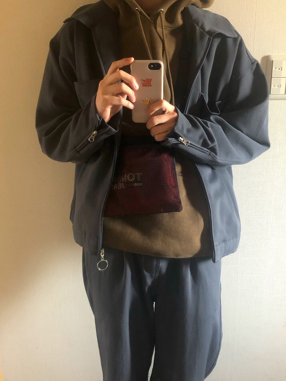 グレー系のセットアップ、レッド系のショルダーバッグ、ブラウン系のパーカーを着用したメンズの春コーディネートの1枚目の写真