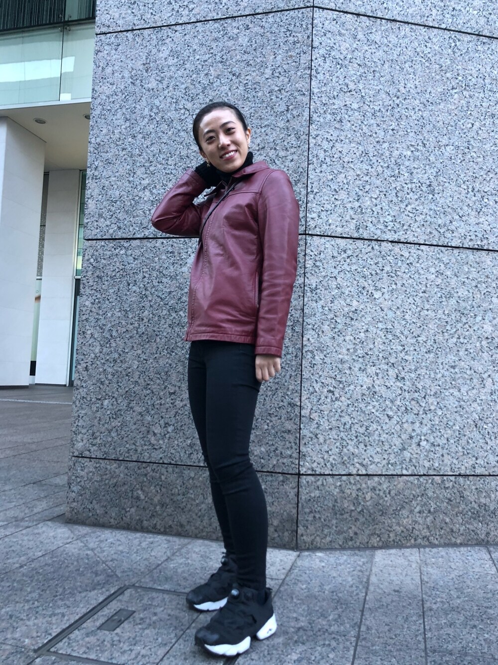 レッド系のライダースジャケット、ブラック系のスニーカーを着用したレディースの春コーディネートの1枚目の写真