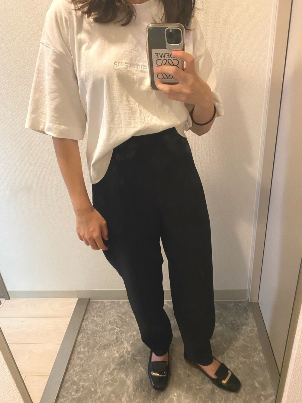 ブラック系のパンツ、ブラック系のパンプス、ホワイト系のTシャツ/カットソーを着用したレディースの夏コーディネートの1枚目の写真