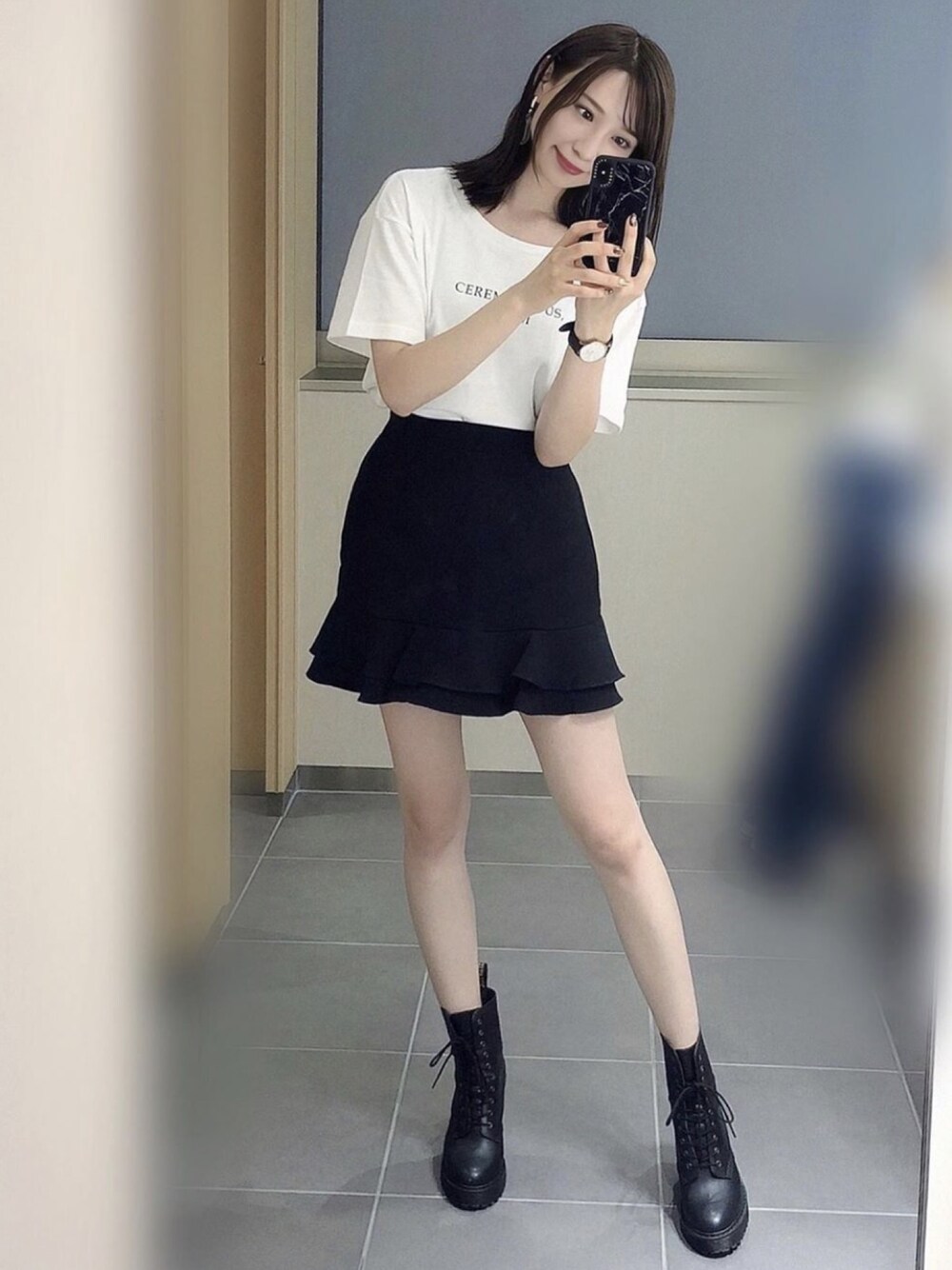 ブラック系のスカート、ホワイト系のTシャツ/カットソー、ブラック系のブーツを着用したレディースの秋コーディネートの1枚目の写真