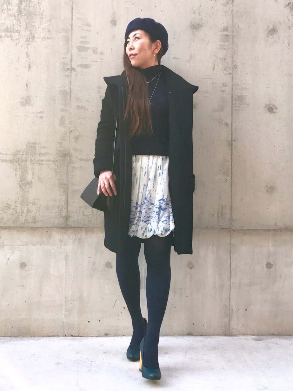 ブルー系のスカート、ブルー系のパンプス、ブラック系のジャケット/アウターを着用したレディースの冬コーディネートの1枚目の写真