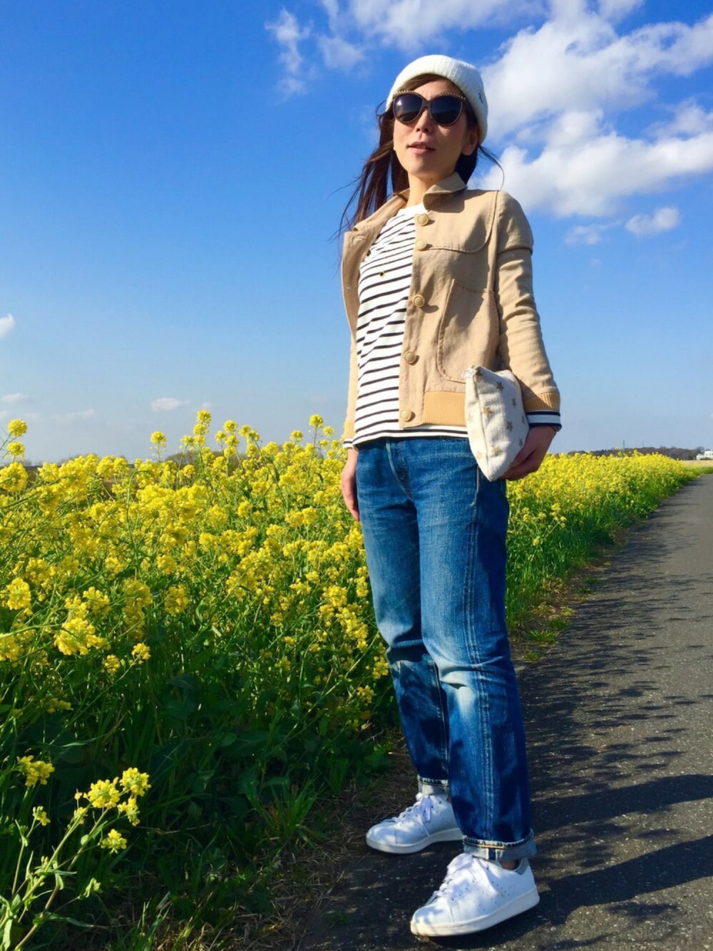ブルー系のデニムパンツ、ホワイト系のスニーカー、ベージュ系のブルゾンを着用したレディースの春コーディネートの1枚目の写真