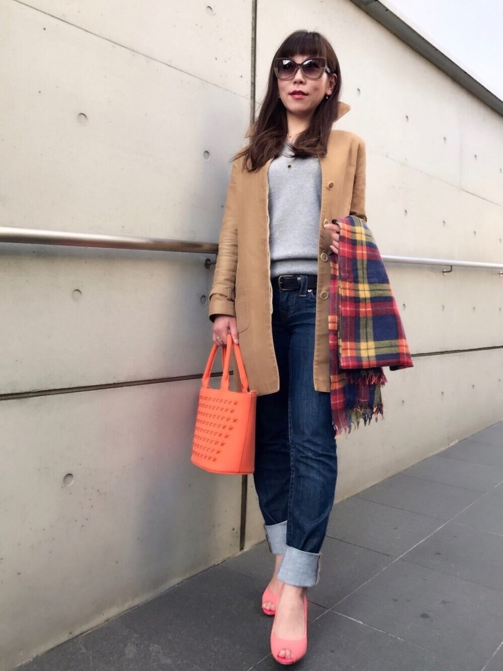 ブルー系のデニムパンツ、ベージュ系のステンカラーコート、ピンク系のパンプスを着用したレディースの冬コーディネートの1枚目の写真