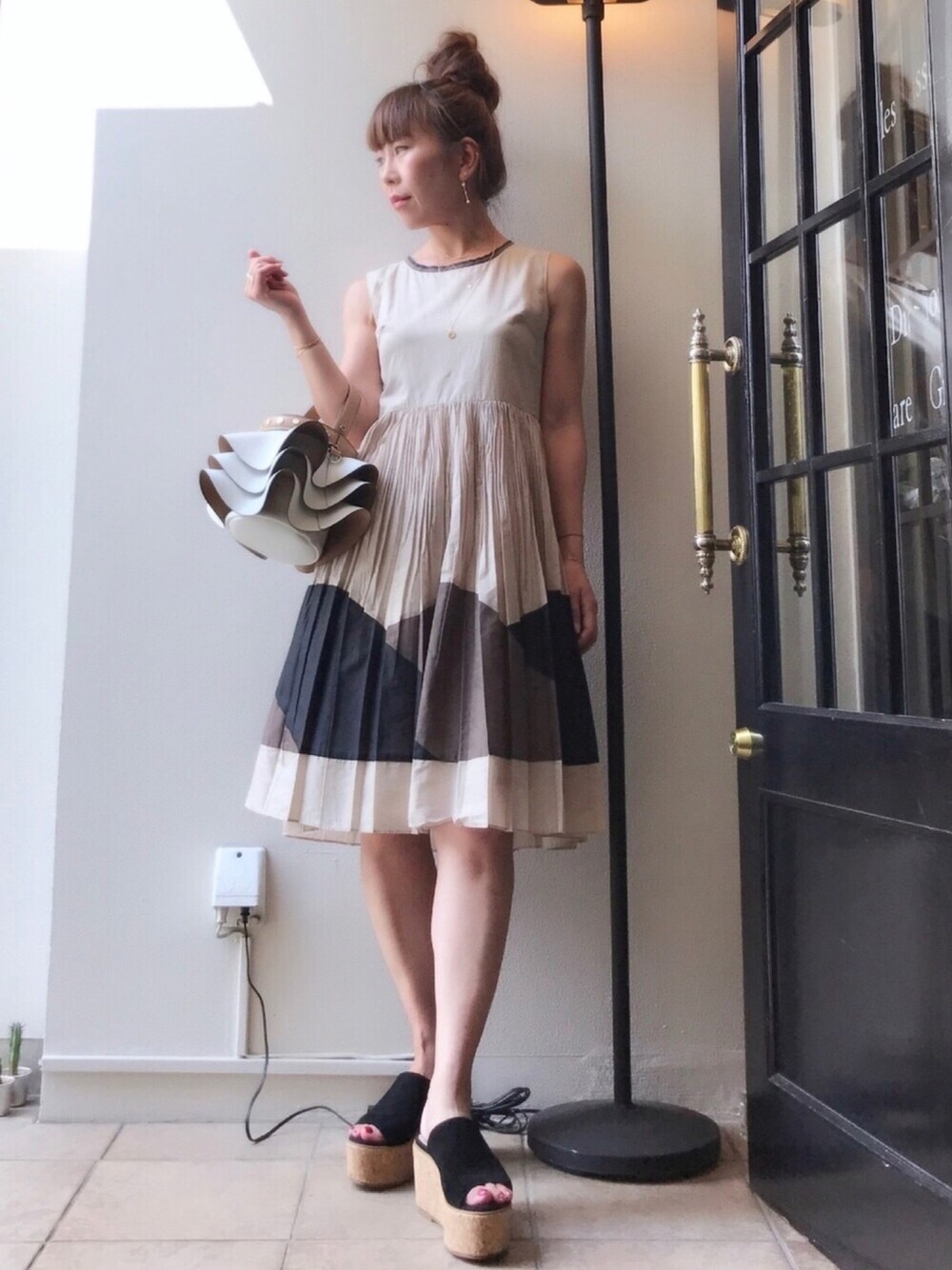ベージュ系のワンピース、ブラック系のサンダル、ホワイト系のショルダーバッグを着用したレディースの夏コーディネートの1枚目の写真