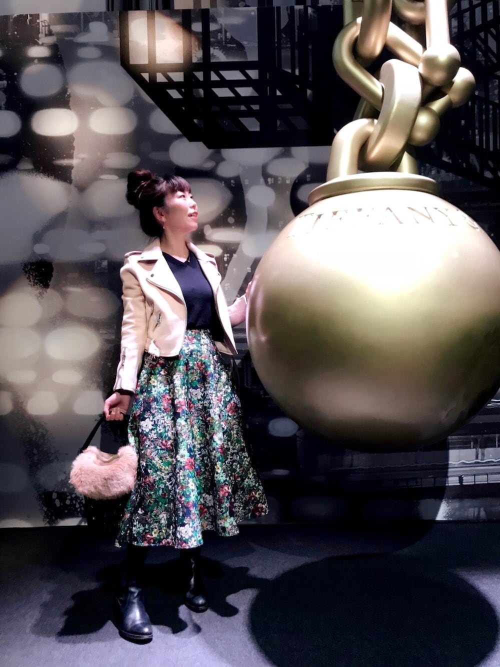 グリーン系のスカート、ピンク系のライダースジャケット、ブラック系のかごバッグを着用したレディースの秋コーディネートの1枚目の写真