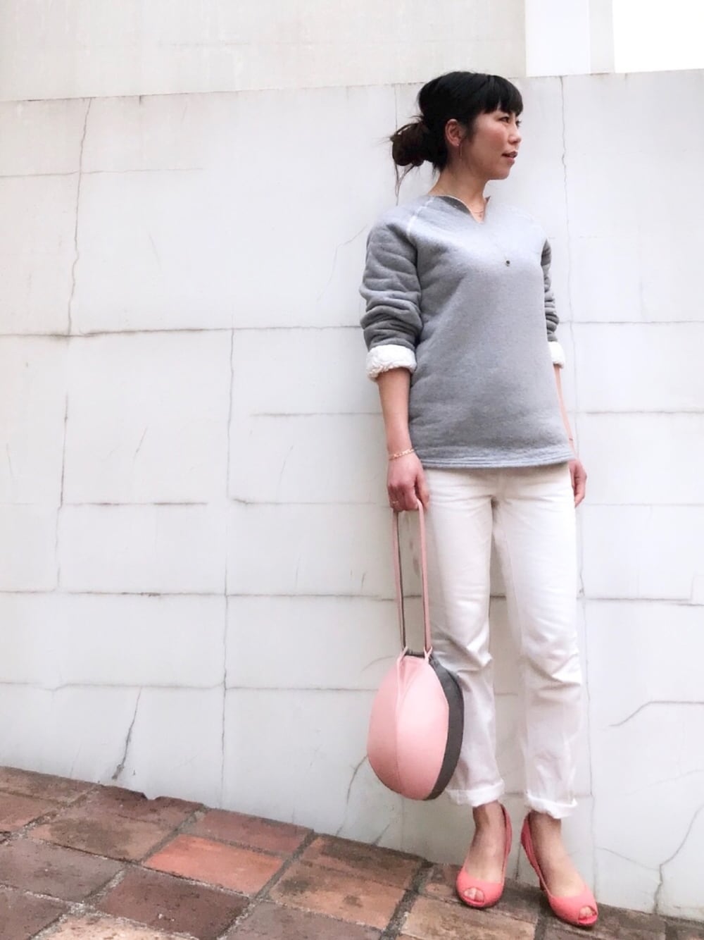 グレー系のスウェット、ホワイト系のデニムパンツ、ピンク系のバッグを着用したレディースの冬コーディネートの1枚目の写真