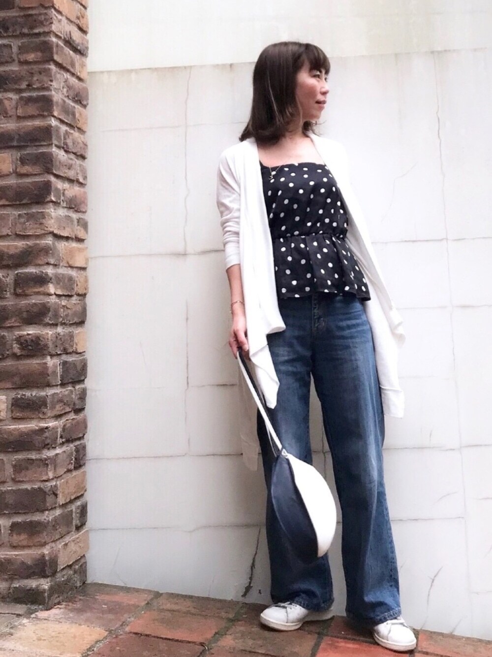 ブルー系のチューブトップ、ホワイト系のカーディガン/ボレロ、ブルー系のデニムパンツを着用したレディースの春コーディネートの1枚目の写真