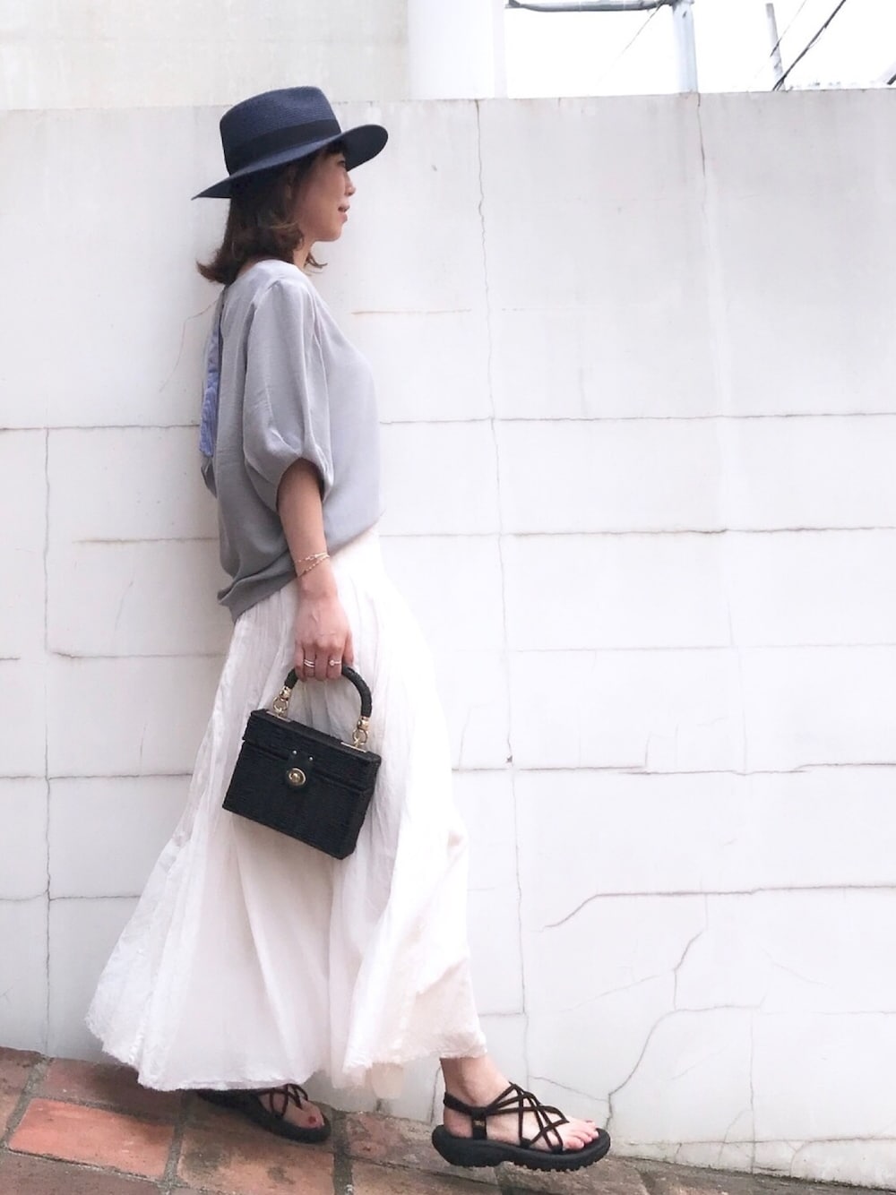 グレー系のシャツ/ブラウス、ホワイト系のスカート、ブラック系のかごバッグを着用したレディースの夏コーディネートの1枚目の写真