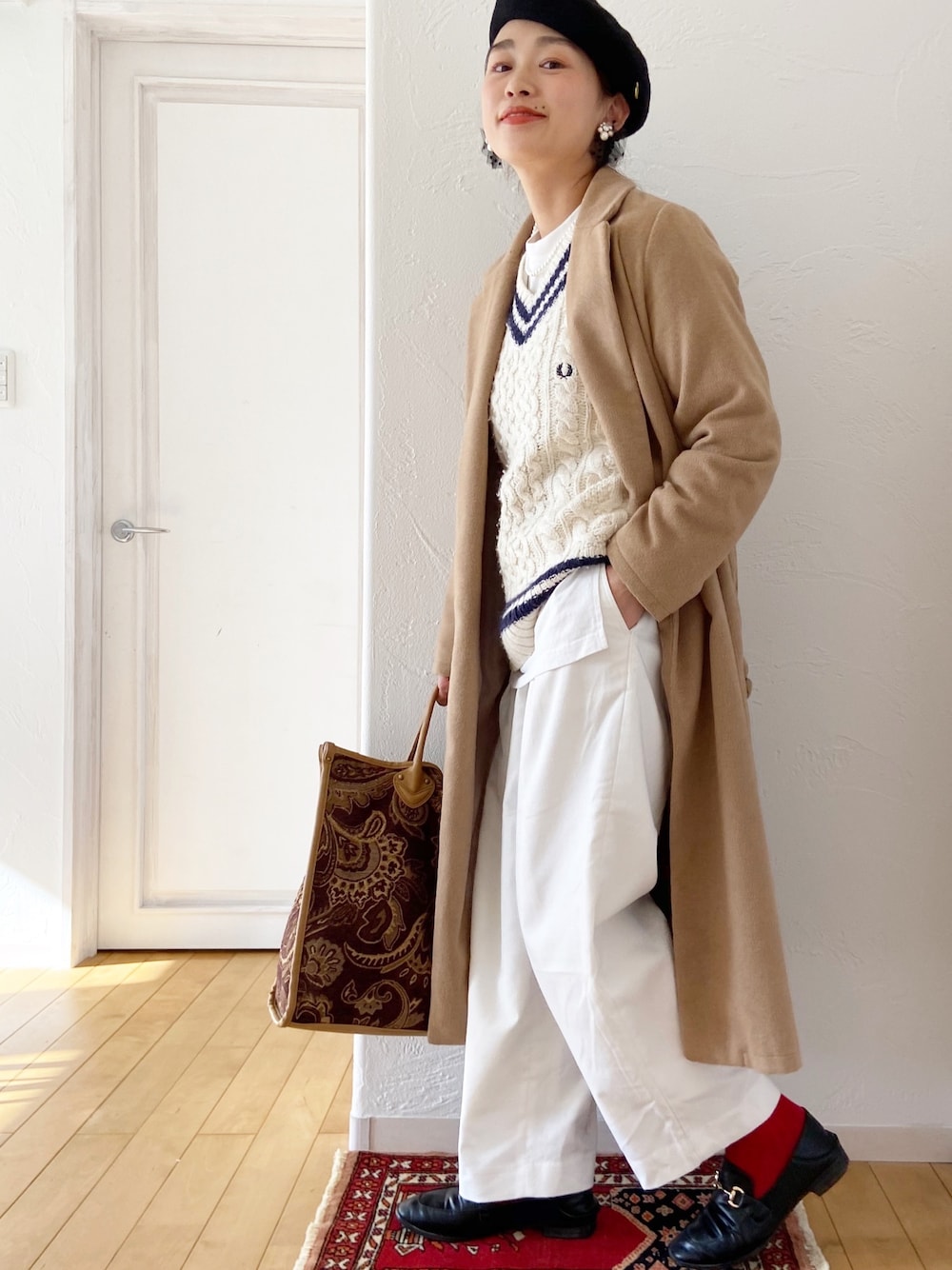 ホワイト系のニット/セーター、ブラウン系のトートバッグ、ブラック系のローファーを着用したレディースの冬コーディネートの1枚目の写真