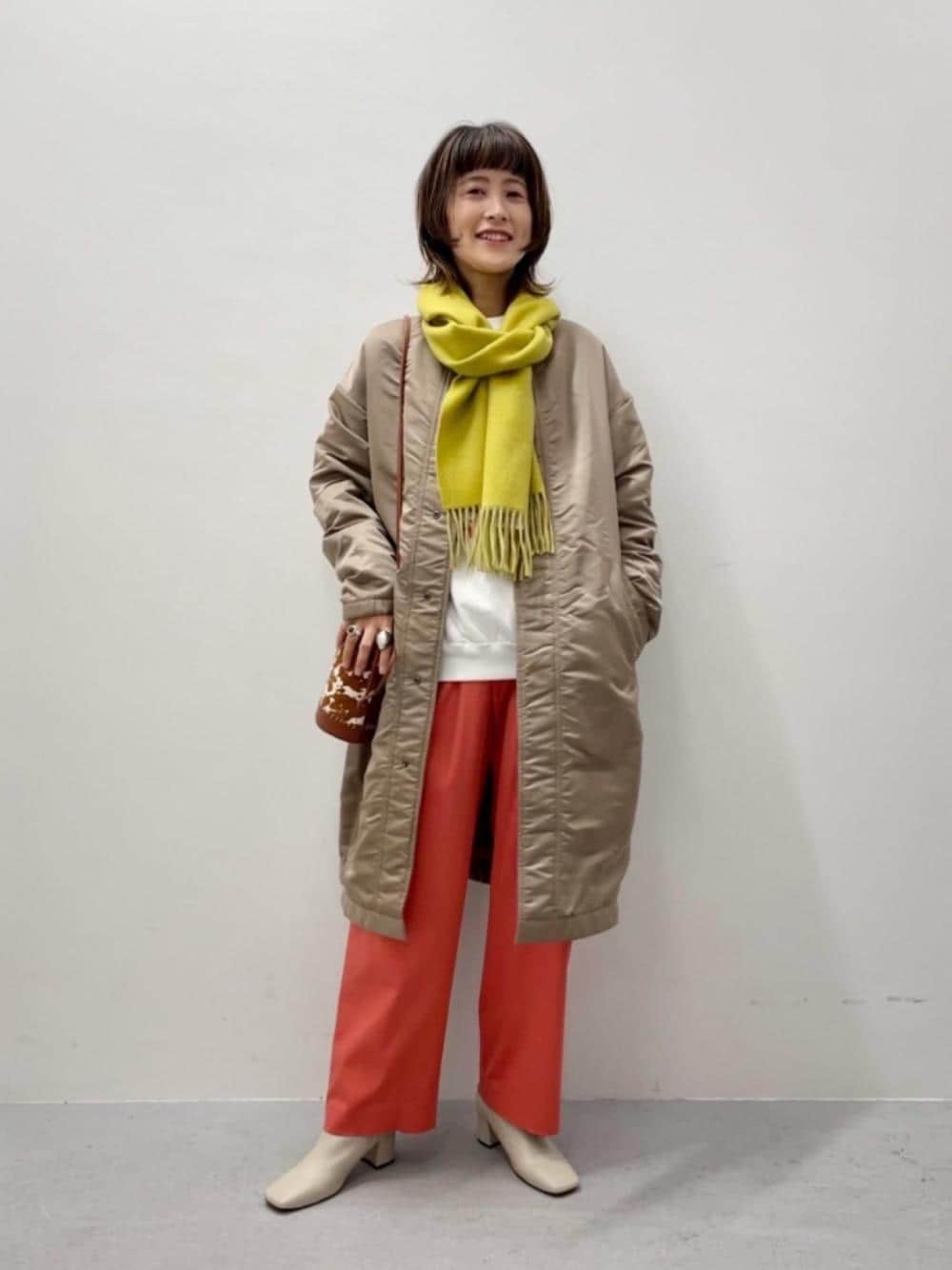 ブラウン系のショルダーバッグ、ブラウン系のその他アウター、オレンジ系のその他パンツを着用したレディースの冬コーディネートの1枚目の写真