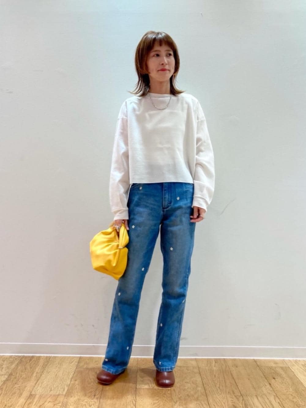 オレンジ系のショルダーバッグ、ブラウン系のサンダル、ブルー系のデニムジャケットを着用したレディースの冬コーディネートの1枚目の写真