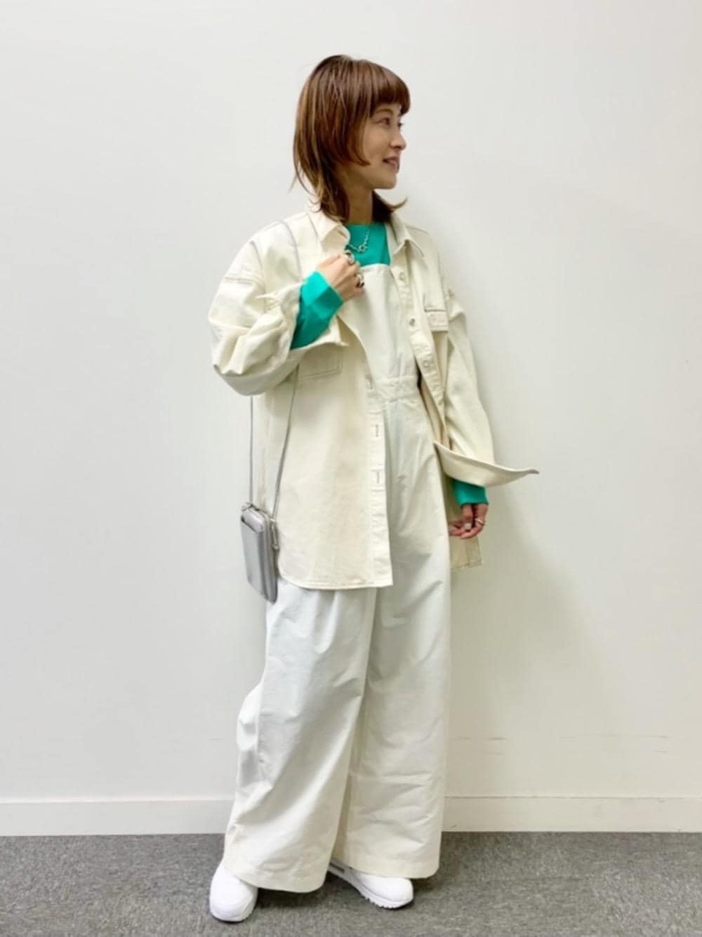 ホワイト系のサロペット/オーバーオール、グリーン系のニット/セーター、ホワイト系のシャツ/ブラウスを着用したレディースの冬コーディネートの1枚目の写真