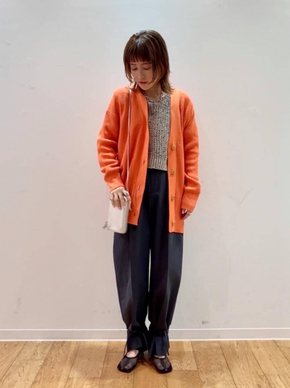 ブラック系のパンプス、ホワイト系のタンクトップ、オレンジ系のカーディガン/ボレロを着用したレディースの冬コーディネートの1枚目の写真