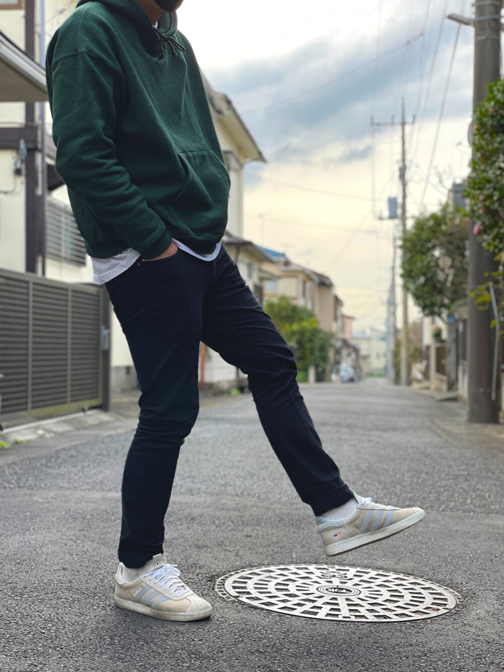 グリーン系のパーカー、ホワイト系のTシャツ/カットソー、ブラック系のチノパンツを着用したメンズの春コーディネートの1枚目の写真