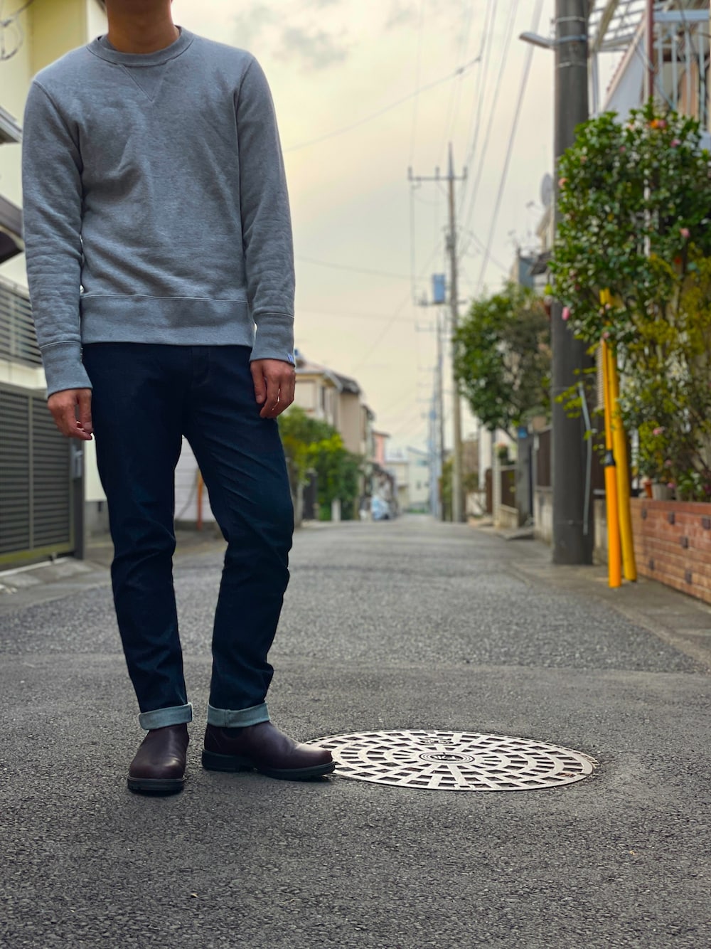 グレー系のスウェット、ブルー系のデニムパンツ、ブラウン系のブーツを着用したメンズの春コーディネートの1枚目の写真