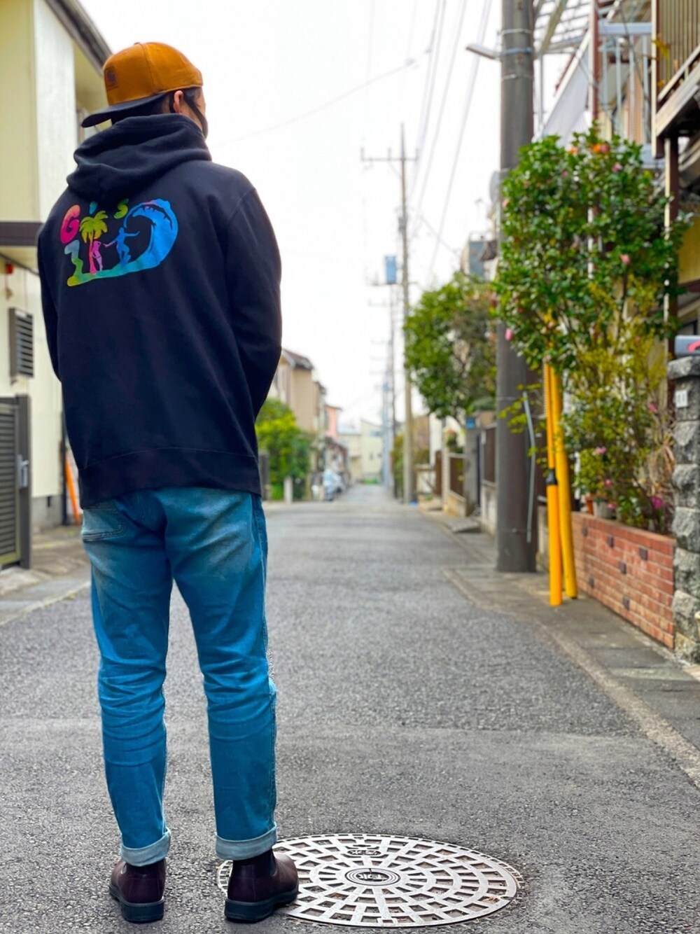 ブラック系のパーカー、ブルー系のデニムパンツ、ブラウン系のブーツを着用したメンズの春コーディネートの1枚目の写真