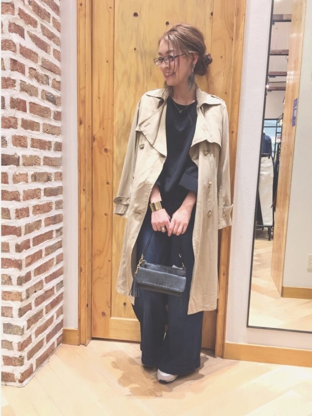 ベージュ系のトレンチコート、ブラック系のシャツ/ブラウス、ブルー系のデニムパンツを着用したレディースの冬コーディネートの1枚目の写真