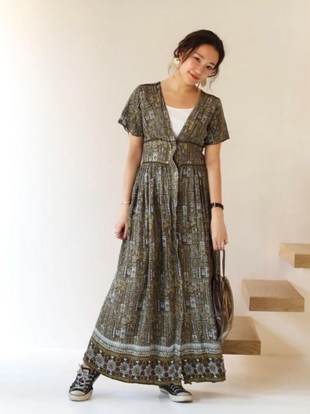 グリーン系のワンピース、グレー系のハンドバッグ、ゴールド系のピアス（両耳用）を着用したレディースの冬コーディネートの1枚目の写真