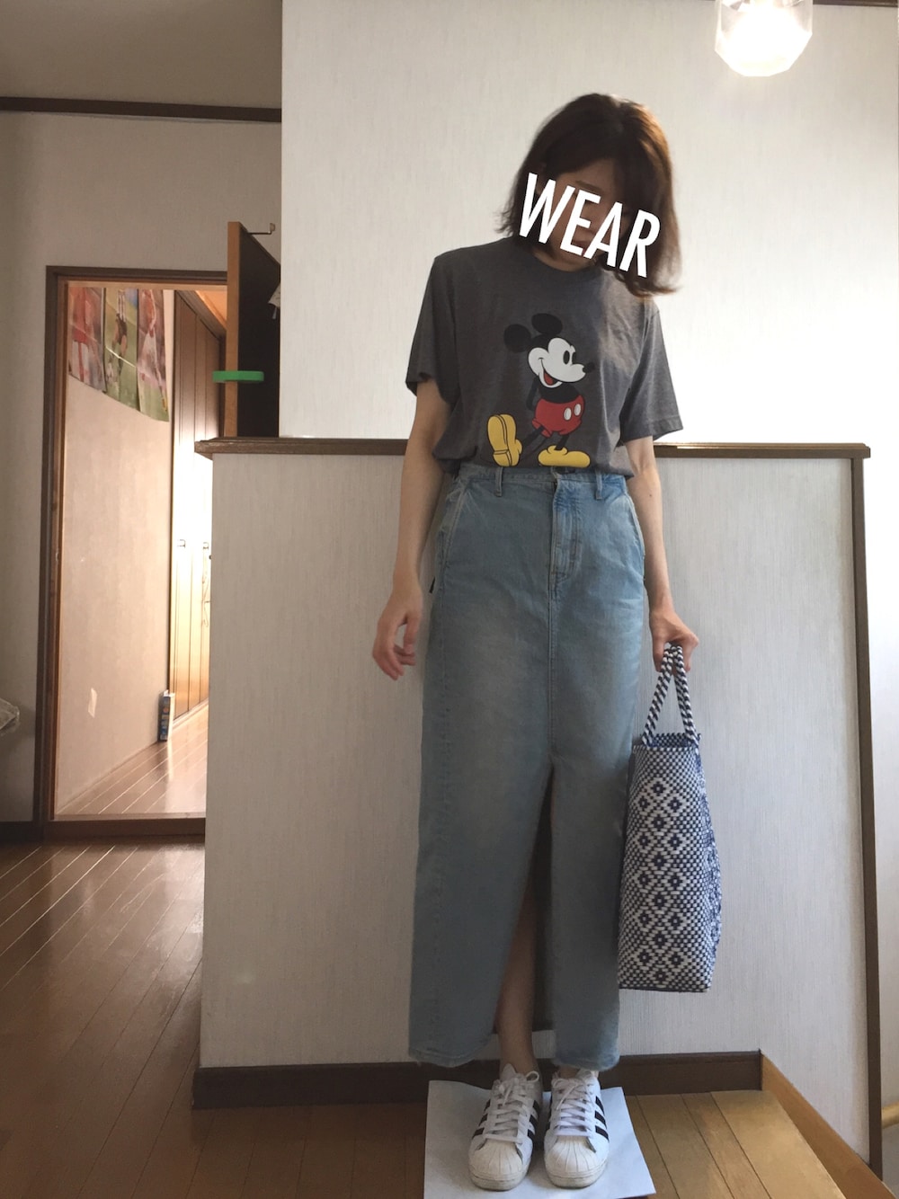 グレー系のTシャツ/カットソー、ブルー系のデニムスカート、ホワイト系のスニーカーを着用したレディースの夏コーディネートの1枚目の写真