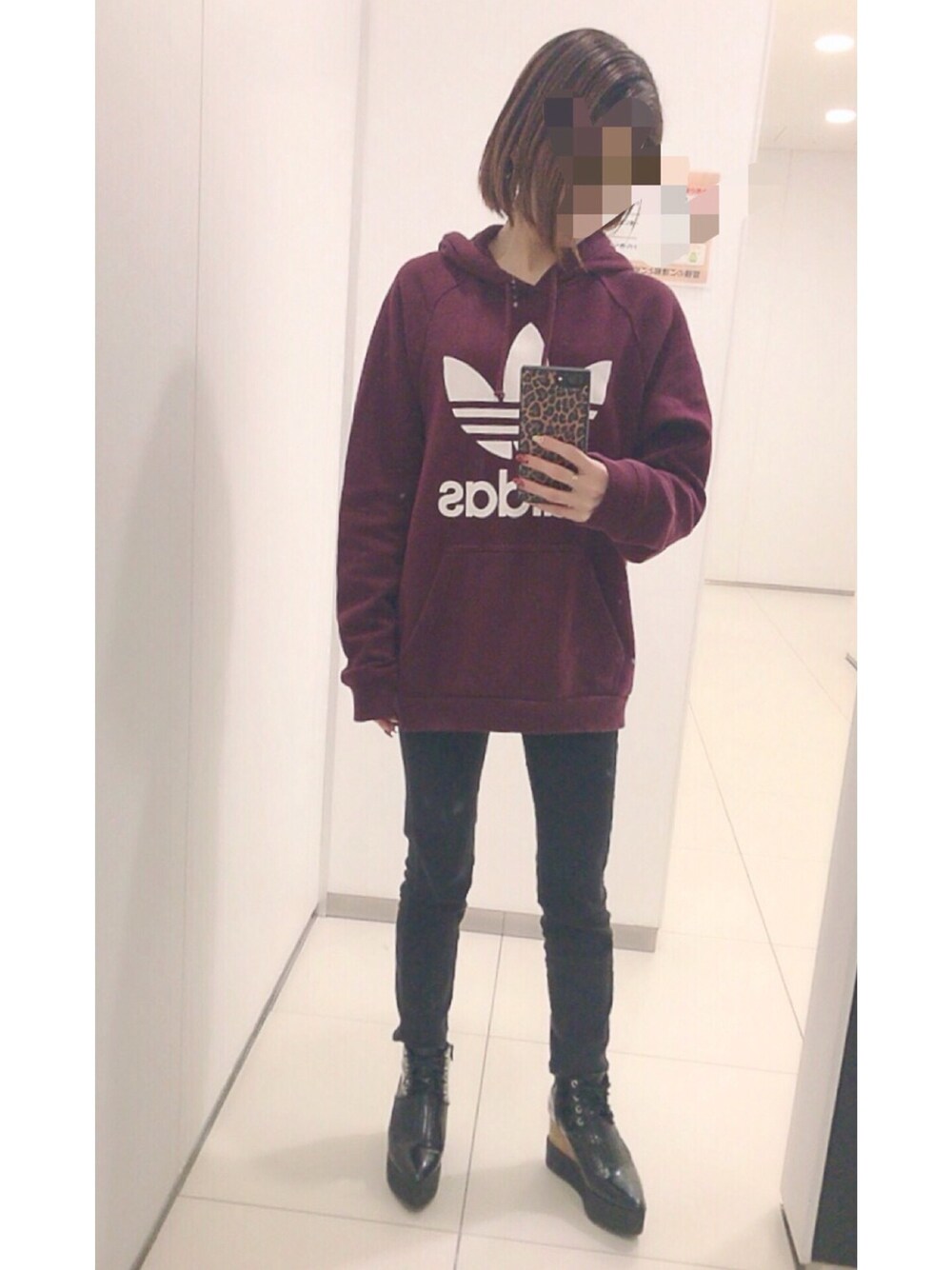 レッド系のパーカー、ブラック系のブーツ、ブラック系のデニムパンツを着用したレディースの春コーディネートの1枚目の写真