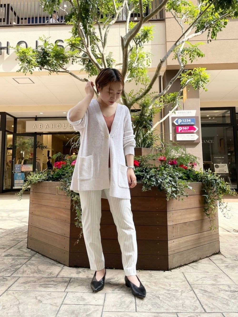 ホワイト系のカーディガン/ボレロ、ブラウン系のタンクトップ、ホワイト系のスラックスを着用したレディースの春コーディネートの1枚目の写真