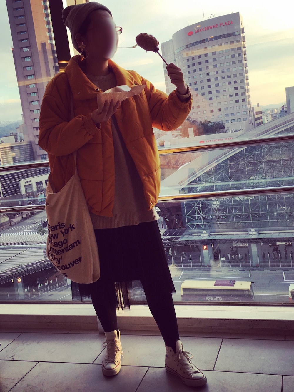 イエロー系のダウンジャケット/コート、ベージュ系のニット/セーター、ブラック系のスカートを着用したレディースの春コーディネートの1枚目の写真