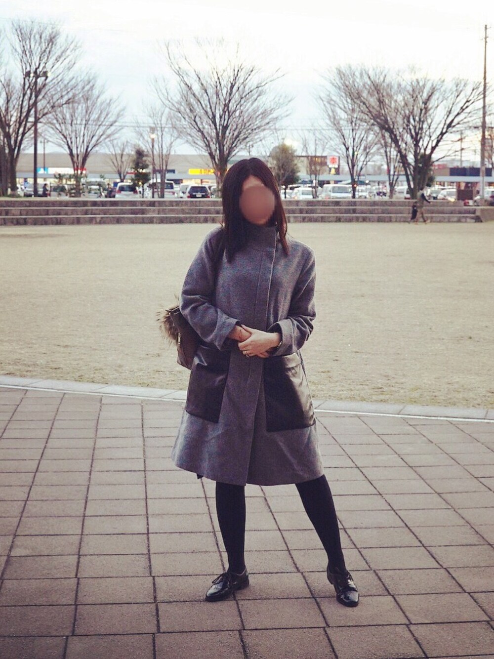 グレー系のステンカラーコート、グレー系のショルダーバッグ、ブラック系のローファーを着用したレディースの冬コーディネートの1枚目の写真