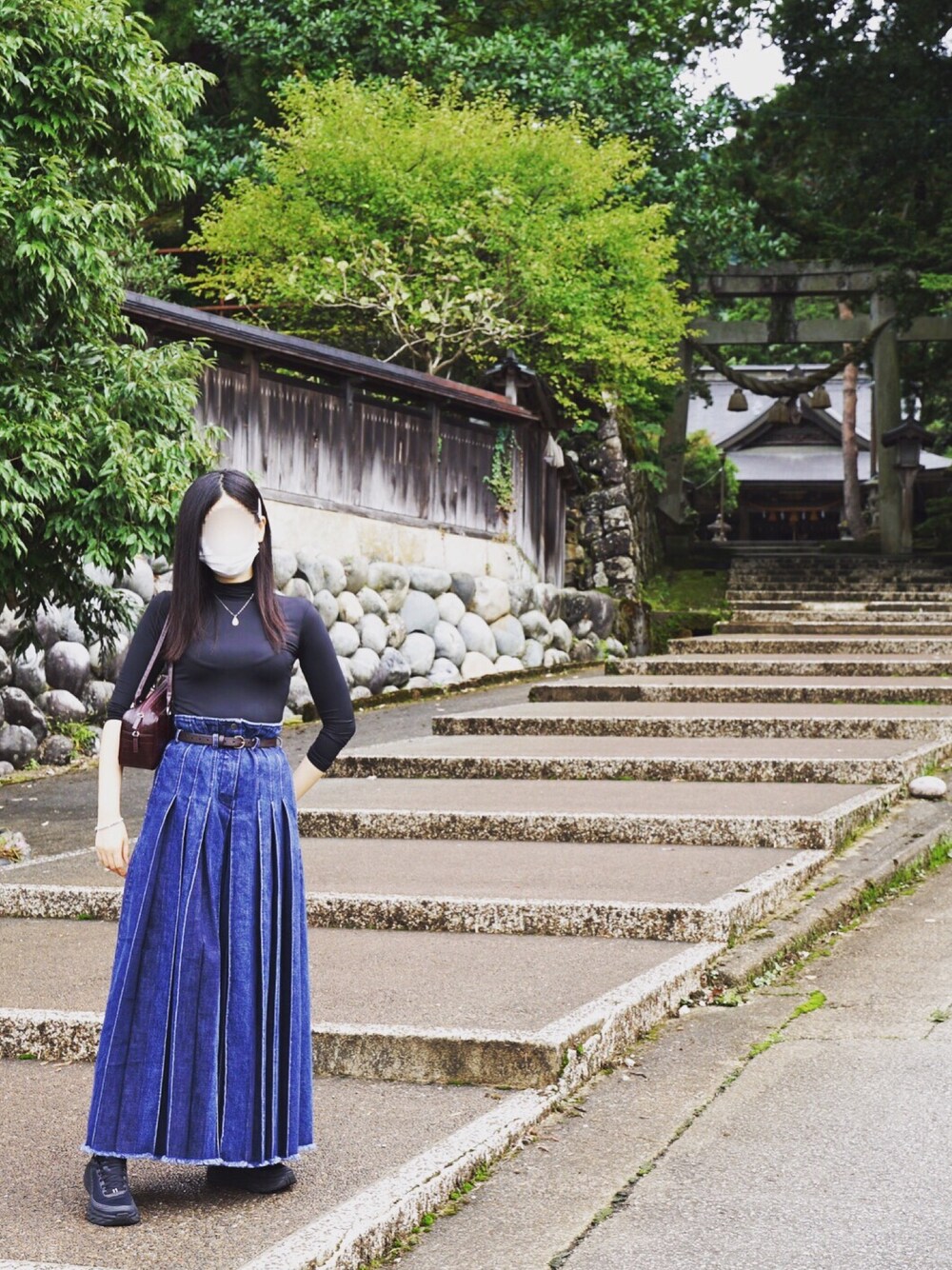 ブラック系のTシャツ/カットソー、ブルー系のデニムパンツ、ブラウン系のハンドバッグを着用したレディースの秋コーディネートの1枚目の写真