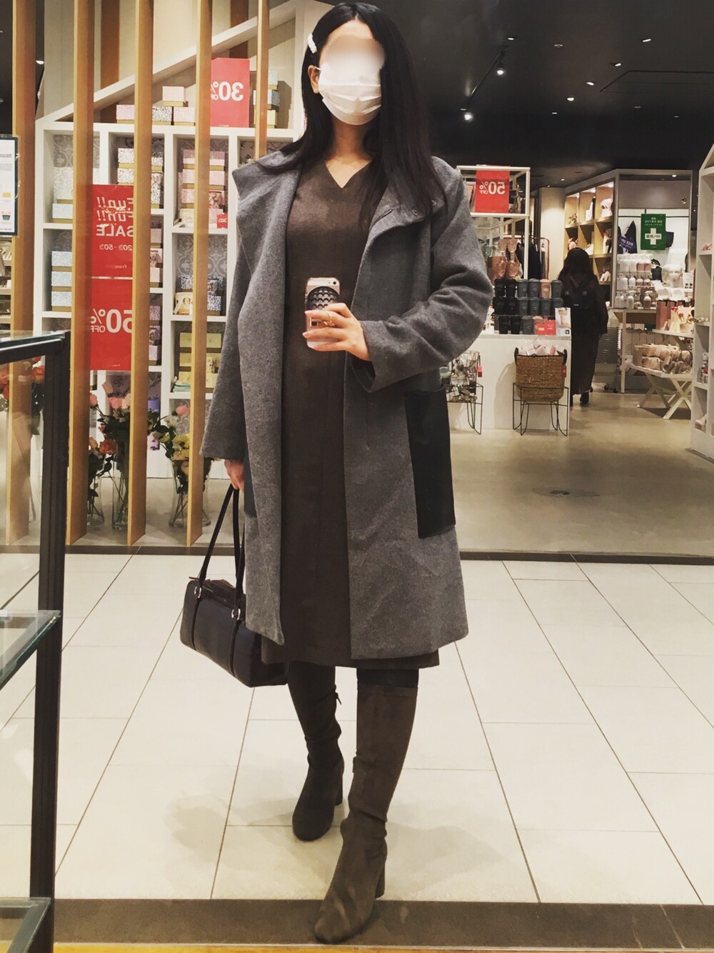 ブラウン系のワンピース、グレー系のステンカラーコート、ブラウン系のブーツを着用したレディースの冬コーディネートの1枚目の写真