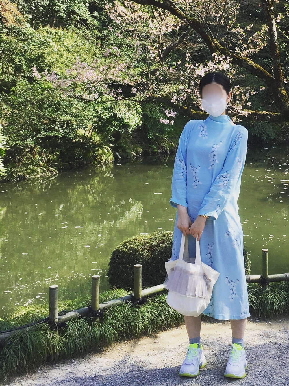 ブルー系のワンピース、ホワイト系のトートバッグ、ホワイト系のスニーカーを着用したレディースの春コーディネートの1枚目の写真