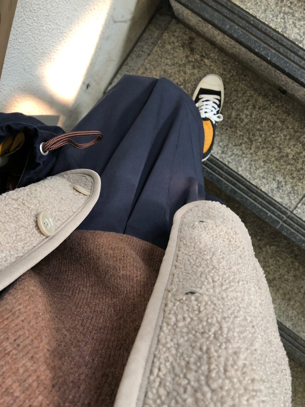 ブラック系のスニーカー、ブルー系のスカート、ブラウン系のニット/セーターを着用したレディースの秋コーディネートの1枚目の写真