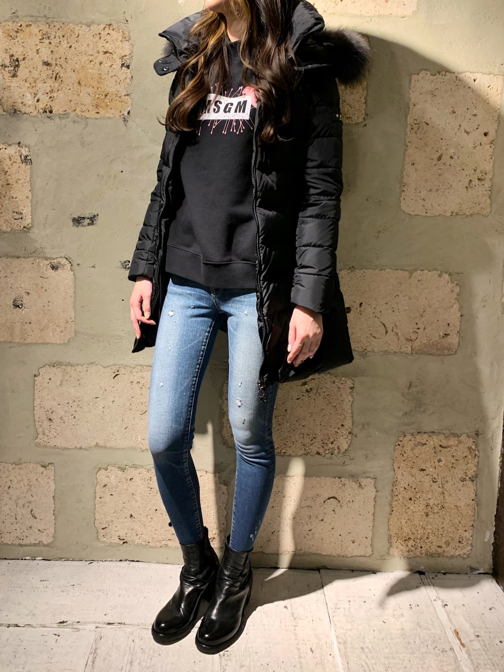 ブラック系のダウンジャケット/コート、ブラック系のTシャツ/カットソー、ブルー系のデニムパンツを着用したレディースの秋コーディネートの1枚目の写真