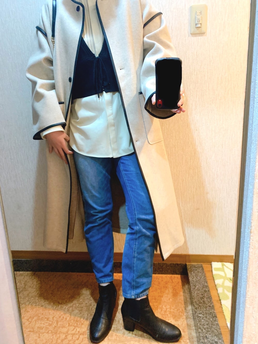 ベージュ系のステンカラーコート、ブラック系のトップス、ホワイト系のシャツ/ブラウスを着用したレディースの春コーディネートの1枚目の写真