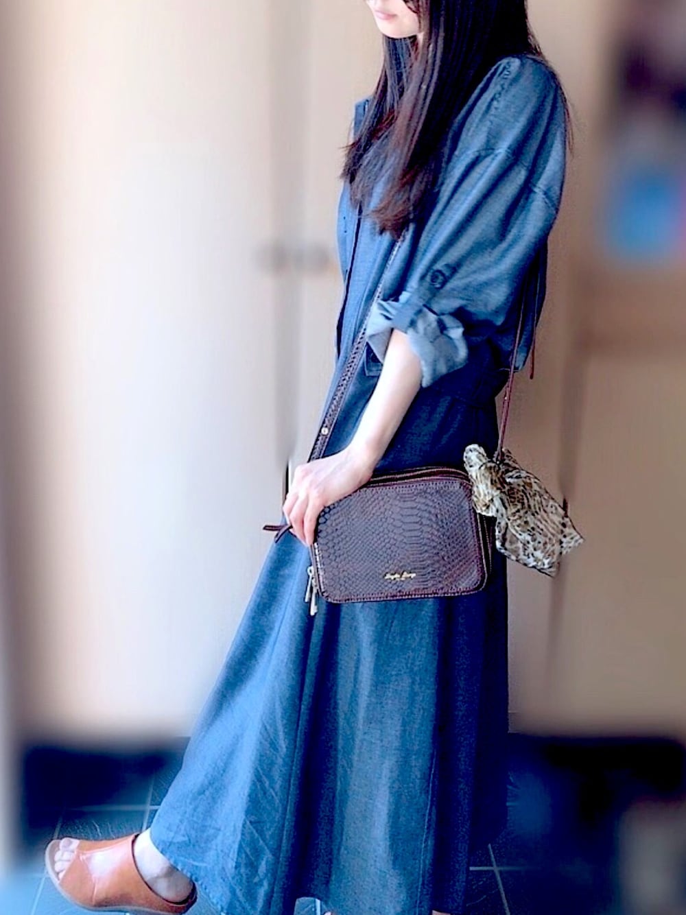 ブルー系のシャツワンピース、ブラウン系のショルダーバッグ、ブラウン系のサンダルを着用したレディースの夏コーディネートの1枚目の写真