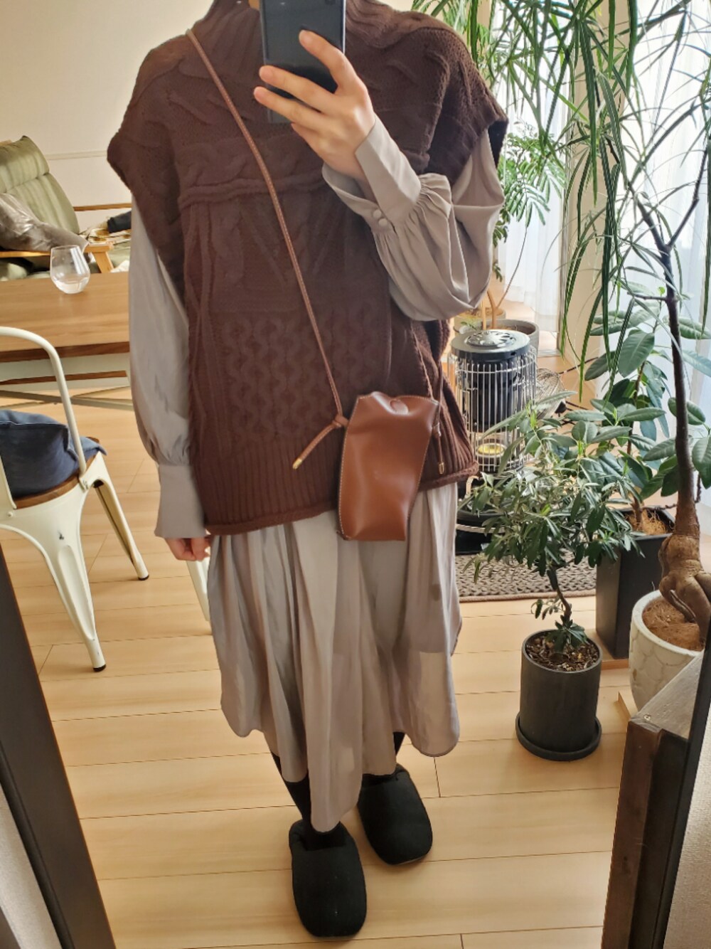ブラウン系のショルダーバッグ、ブラウン系のベスト、ベージュ系のワンピースを着用したレディースの冬コーディネートの1枚目の写真
