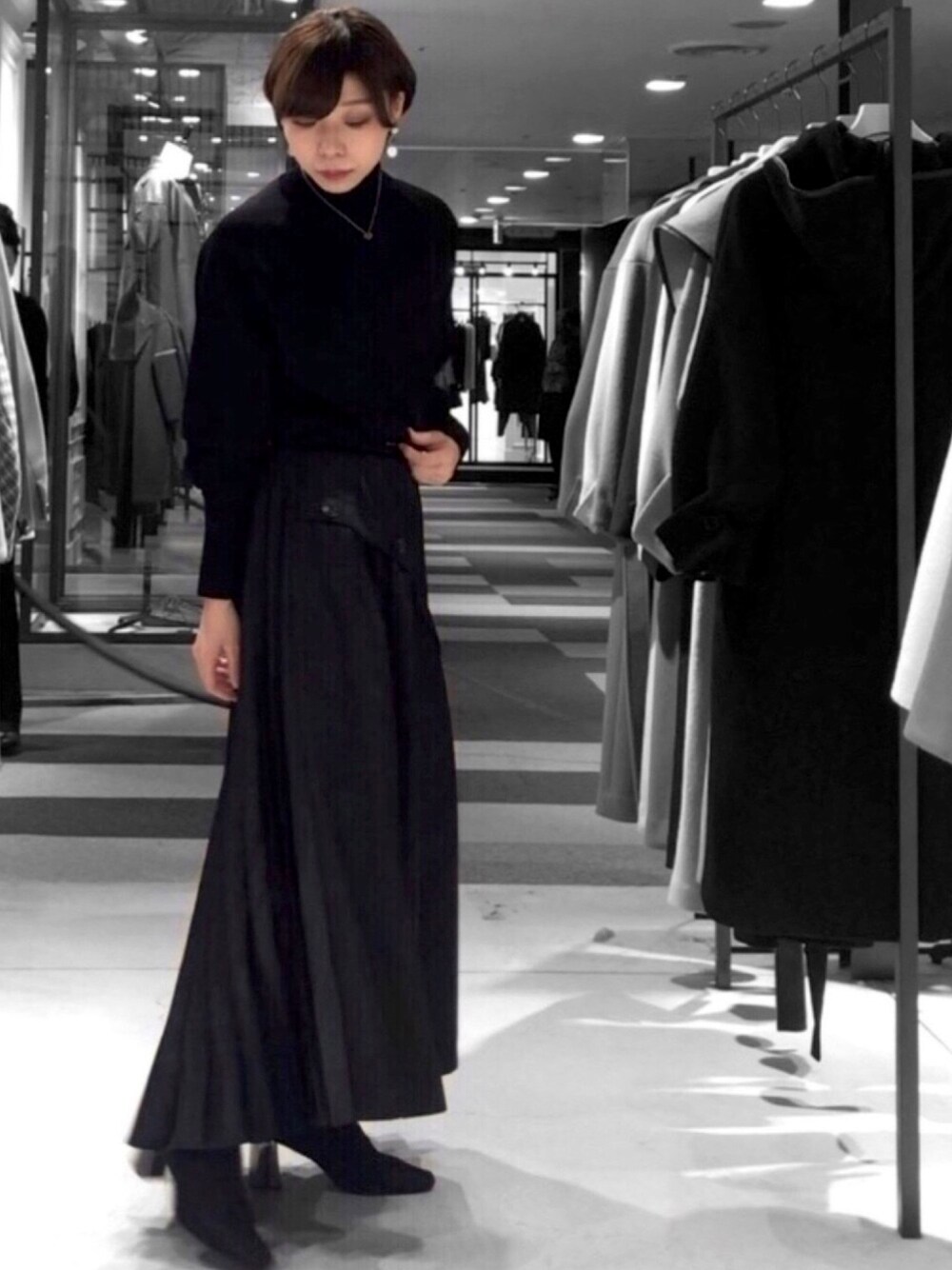 ブラック系のニット/セーター、ブラック系のスカートを着用したレディースの秋コーディネートの1枚目の写真