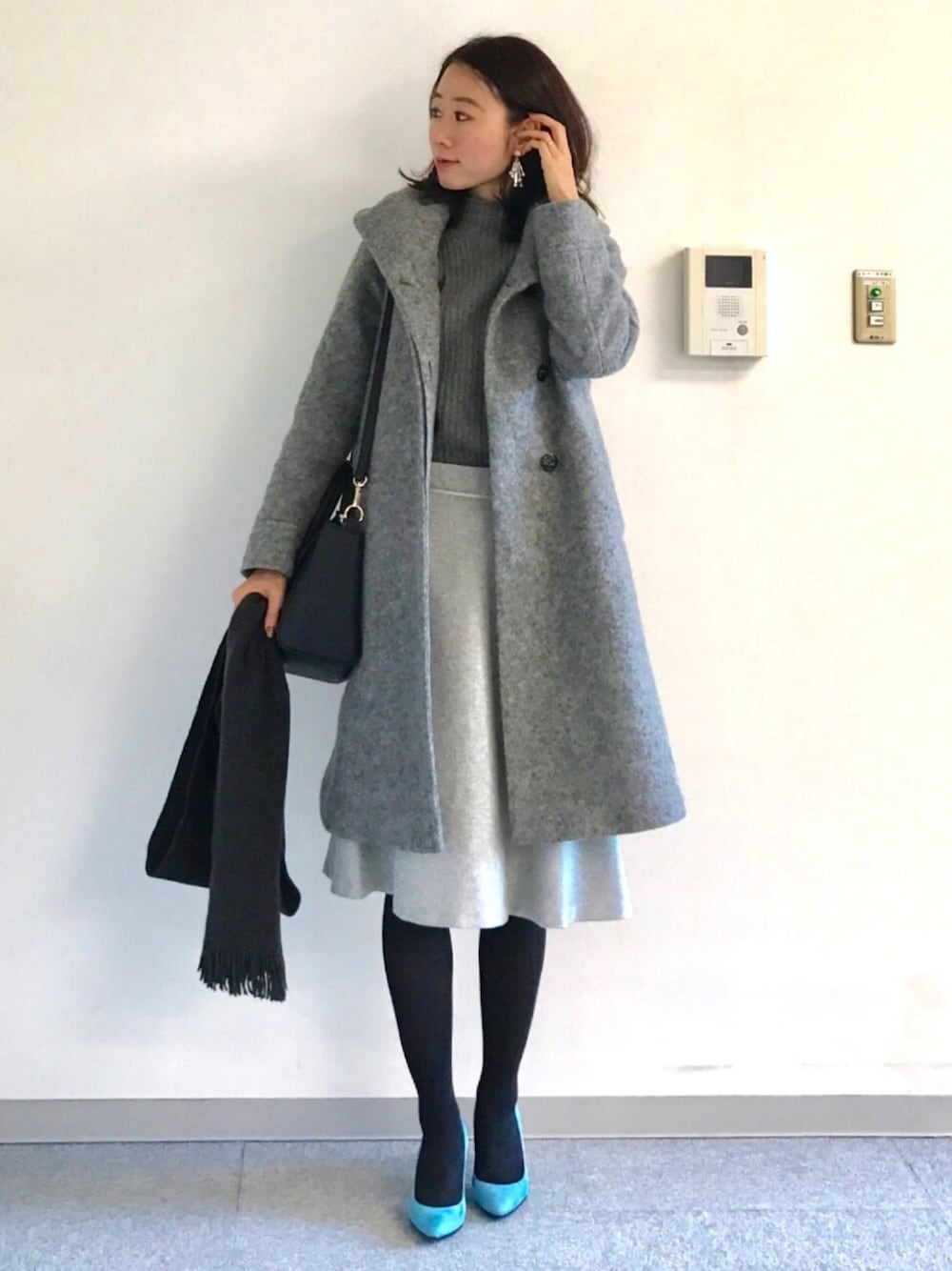 グレー系のニット/セーター、グレー系のスカート、ブルー系のパンプスを着用したレディースの冬コーディネートの1枚目の写真
