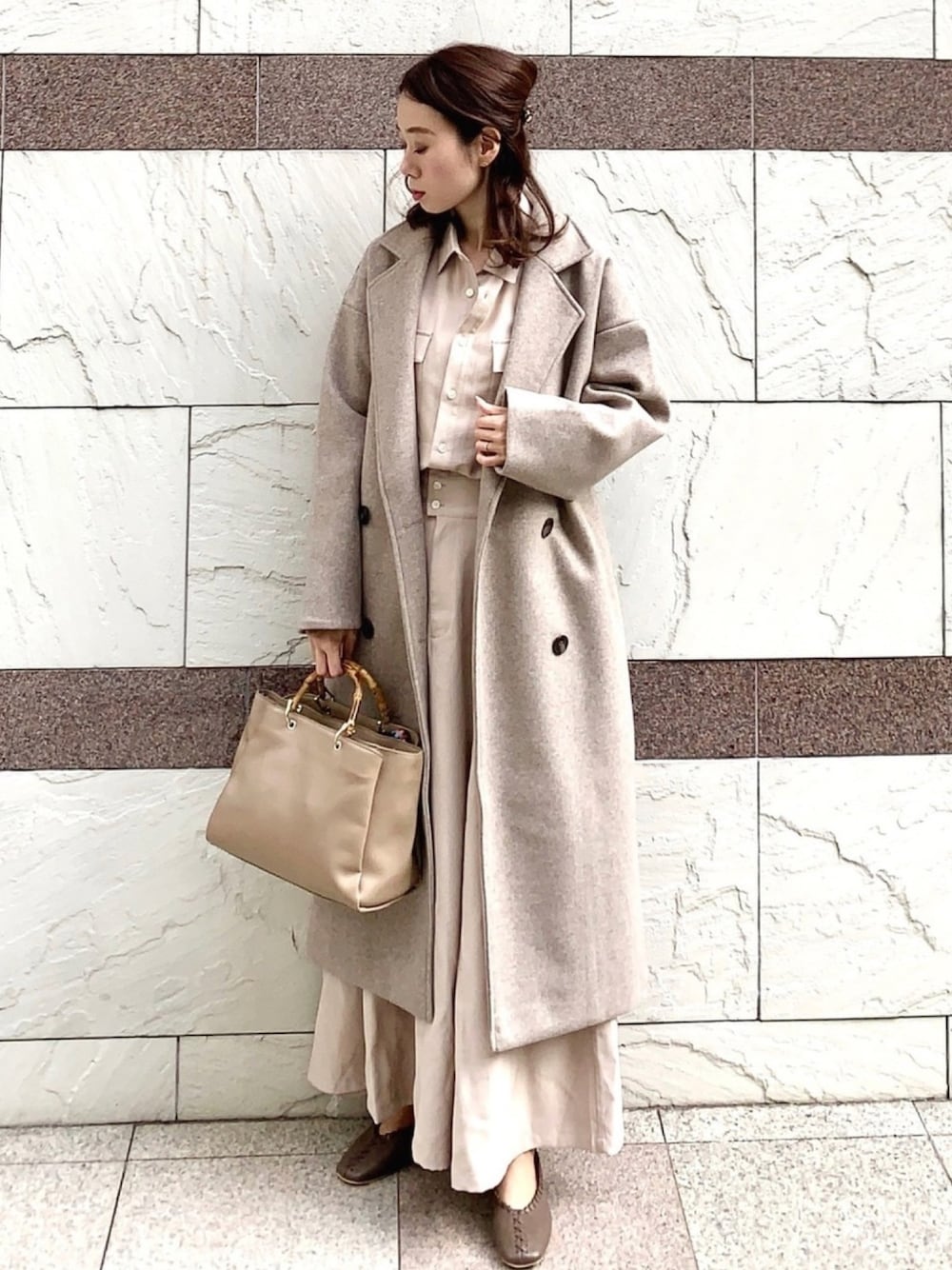 ベージュ系のワンピース、ベージュ系のチェスターコート、ブラウン系のトートバッグを着用したレディースの冬コーディネートの1枚目の写真