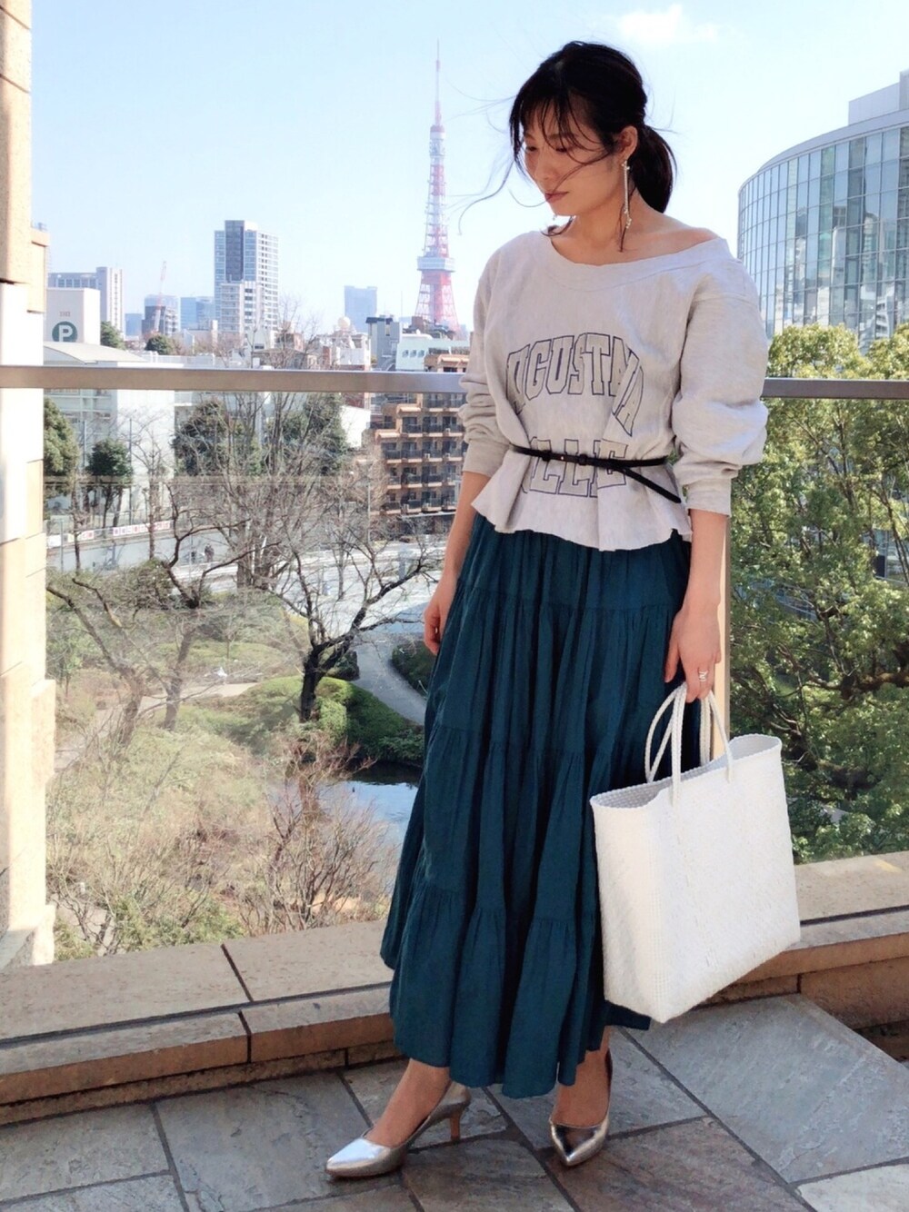 グレー系のスウェット、グリーン系のスカート、ホワイト系のトートバッグを着用したレディースの春コーディネートの1枚目の写真