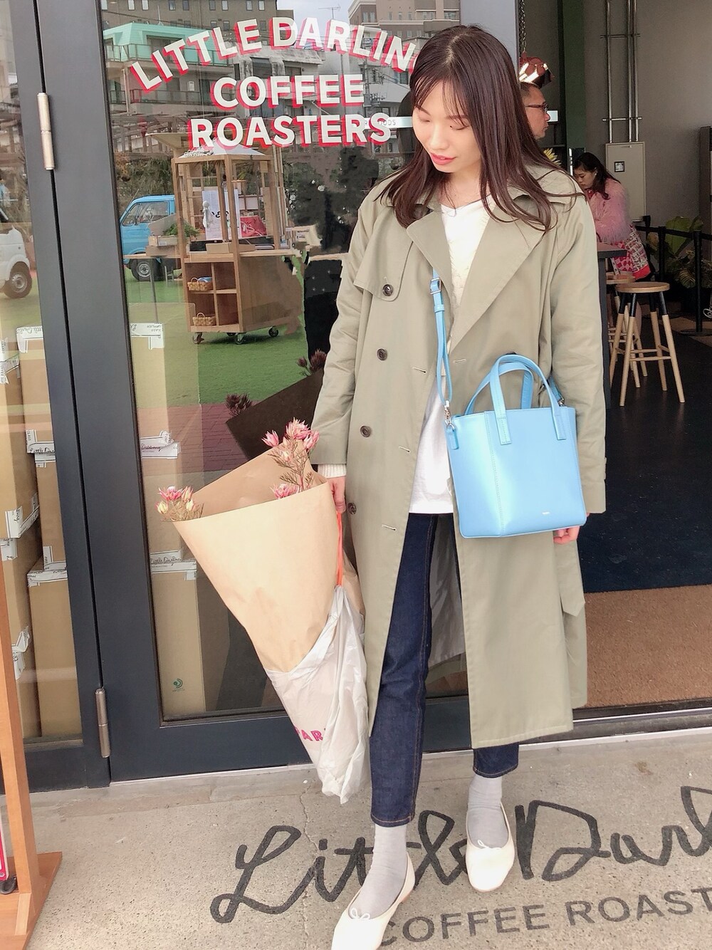グリーン系のトレンチコート、ブルー系のデニムパンツ、ブルー系のショルダーバッグを着用したレディースの春コーディネートの1枚目の写真