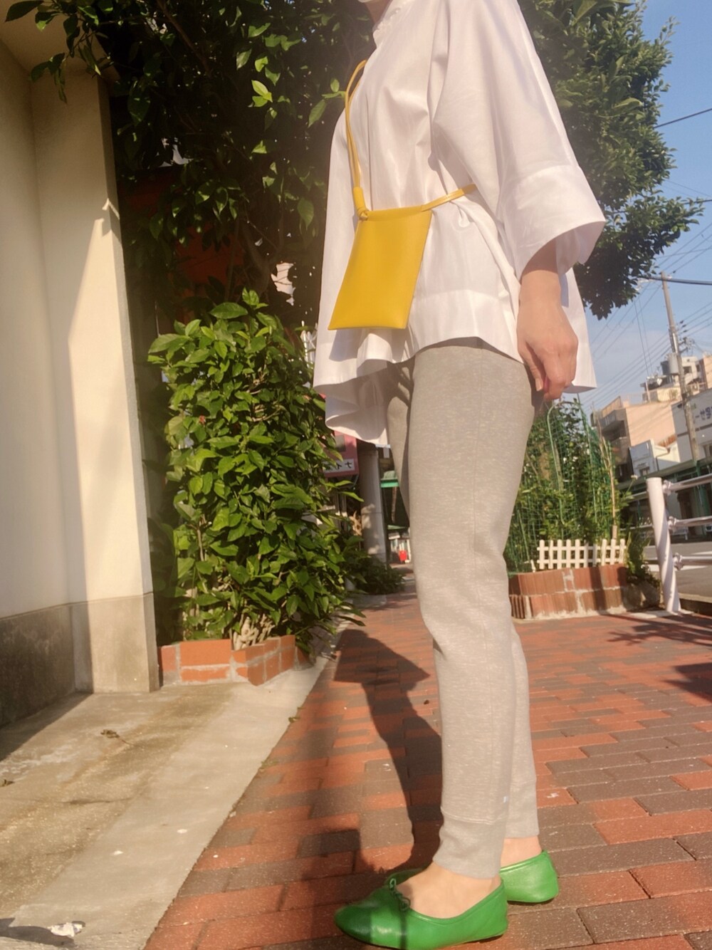 グレー系のスウェットパンツ、ホワイト系のシャツ/ブラウス、イエロー系のバッグを着用したレディースの春コーディネートの1枚目の写真
