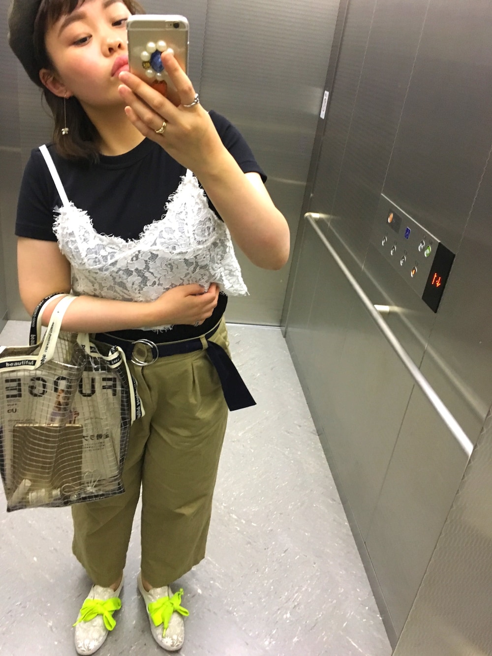 ブラック系のショルダーバッグ、ベージュ系のチノパンツ、ホワイト系のスニーカーを着用したレディースの春コーディネートの1枚目の写真
