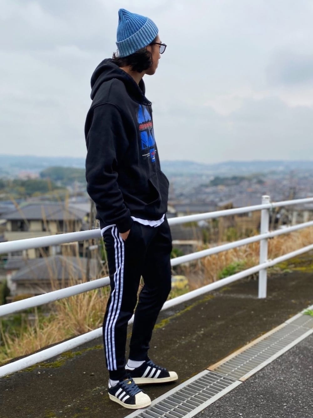 ブラック系のパーカー、ブラック系のその他パンツ、ブラック系のスニーカーを着用したメンズの春コーディネートの1枚目の写真