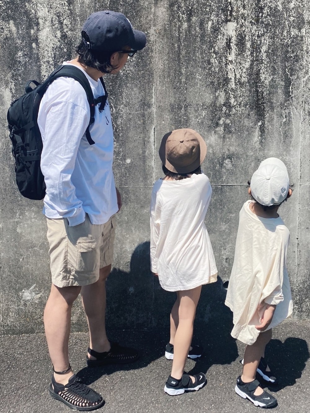 ホワイト系のTシャツ/カットソー、ブラック系のバックパック/リュック、ベージュ系のカーゴパンツを着用したメンズの春コーディネートの1枚目の写真