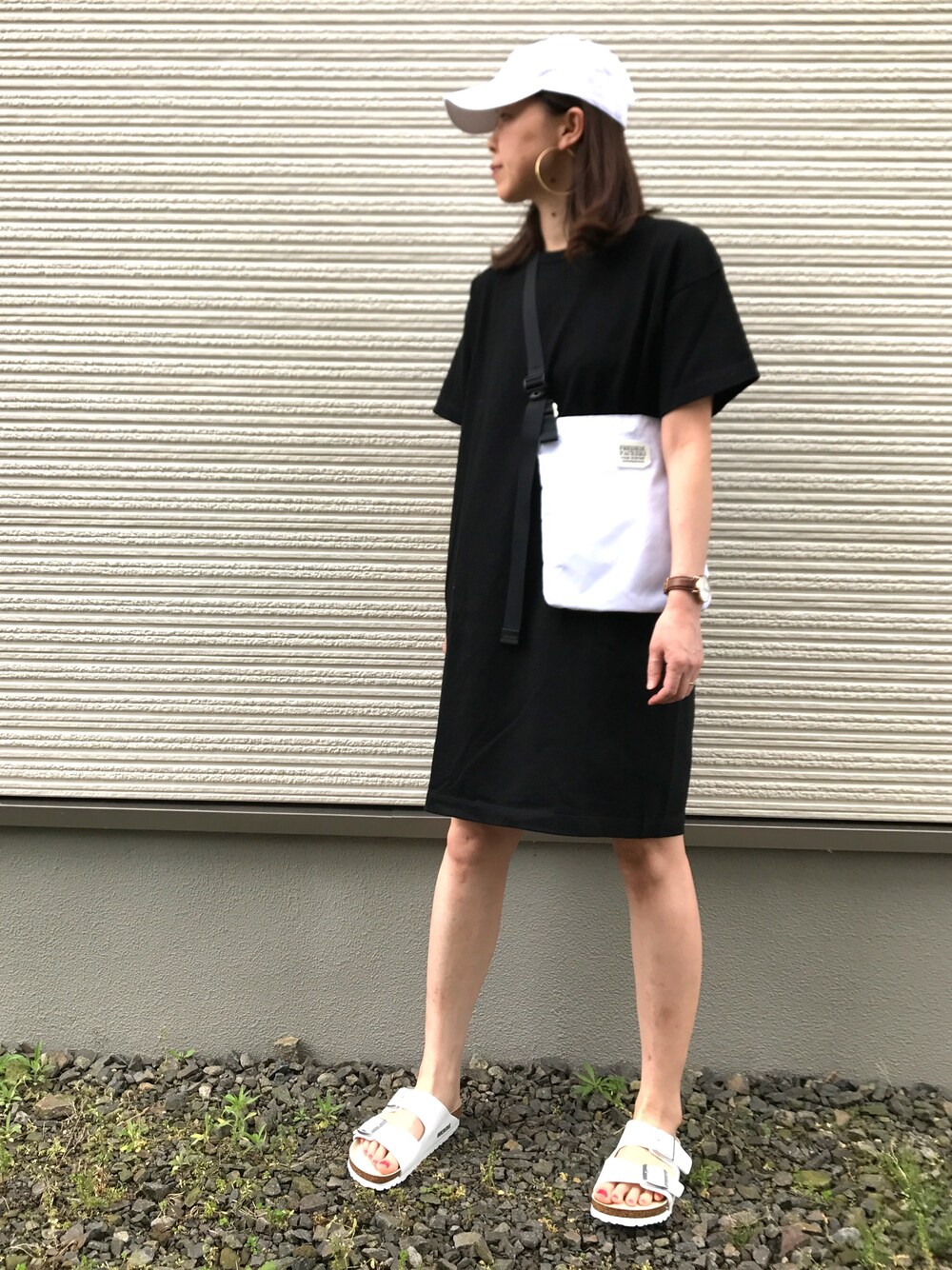 ブラック系のワンピース、ホワイト系のショルダーバッグ、ホワイト系のサンダルを着用したレディースの夏コーディネートの1枚目の写真